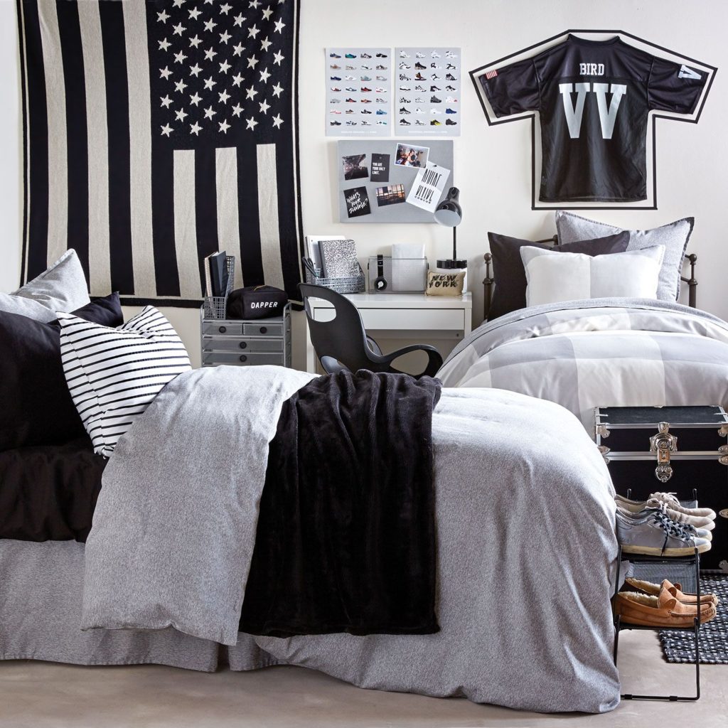 A bedroom with a black and white american flag on the wall
